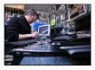 Un technicien de chez Axe Computer démonte la carte mère d'un ordinateur portable afin de recycler ses composantes électroniques.