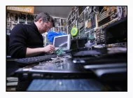 Un technicien de chez Axe Computer démonte la carte mère d'un ordinateur portable afin de recycler ses composantes électroniques.